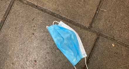 Ett munskydd ligger som skräp på gatan