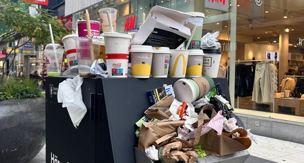 Skräp väller ut från en överfull papperskorg på stan