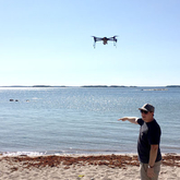 En drönare flyger över en strand för att mäta skräp