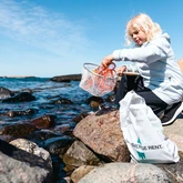 Barn plockar upp skräp ut havet med en håv