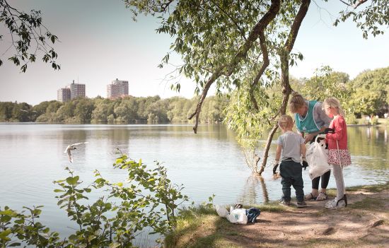 En kvinna och två barn plockar skräp vid en sjö
