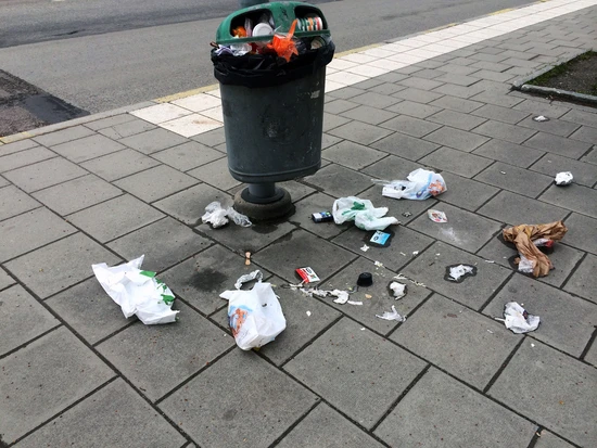 Överfull papperskorg i stadsmiljö