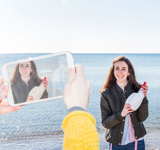 Ung reporter med plastflaska blir filmad på strand. Foto: Jenny Brandt