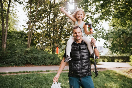 Flicka sitter på pappas axlar