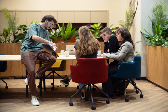 Arbetskollegor som diskuterar vid ett skrivbord