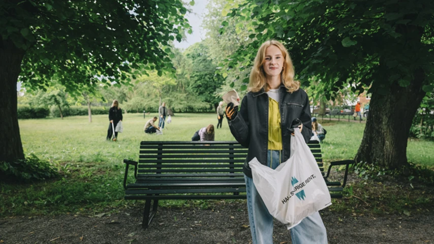 Ung tjej plockar skräp i park